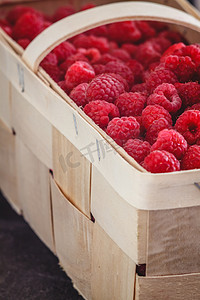 深色复古风的篮子里放着鲜亮多汁的成熟红树莓