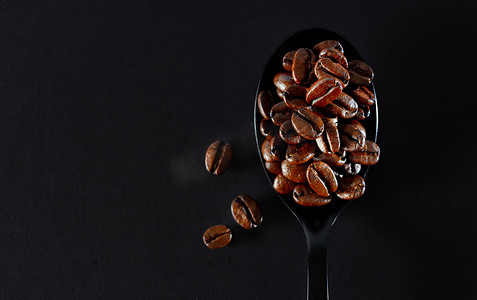黑色勺子上的烤咖啡豆