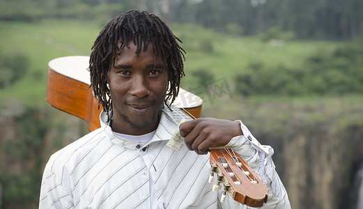 非洲街头艺人肩扛吉他，手拿十兰特纸币