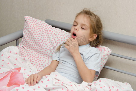 枕头摄影照片_生病躺在床上咳嗽的女孩