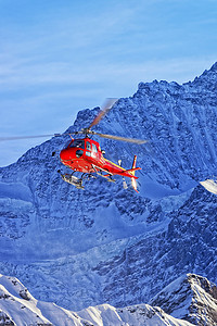 冬季阳光下瑞士阿尔卑斯山的红色直升机
