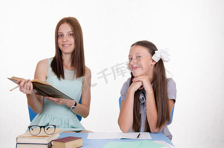 老师卷首语摄影照片_坐在桌旁的学生和老师