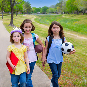 金发孩子走路摄影照片_孩子们带着运动球走路去学校的女孩