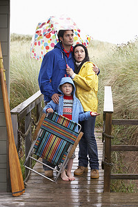 伞下的男孩摄影照片_沙滩上的一家人撑着伞