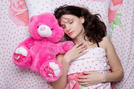 睡觉的枕头摄影照片_抱着泰迪熊睡觉的女孩