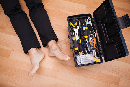 用 DIY 工具赤脚躺在地板上的杂工