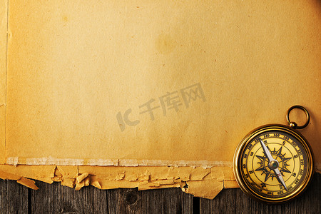 航海复古背景摄影照片_在老背景的古色古香的黄铜指南针