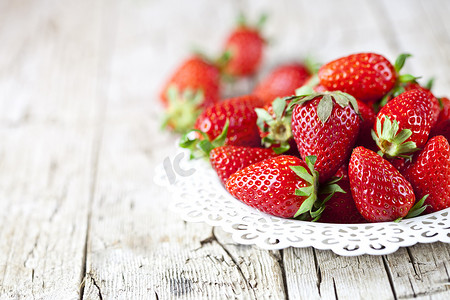 质朴的木制背景上白盘子上的有机红草莓