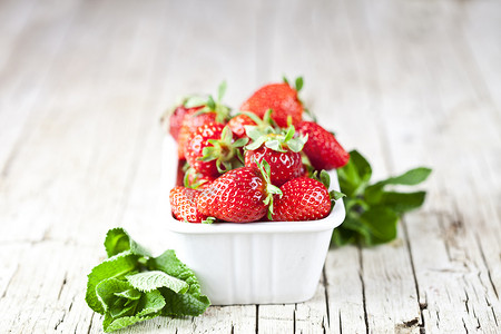 白碗里的新鲜红草莓和质朴的 w 上的薄荷叶