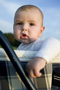婴儿坐婴儿车摄影照片_六个月大的可爱小男孩坐在婴儿车上