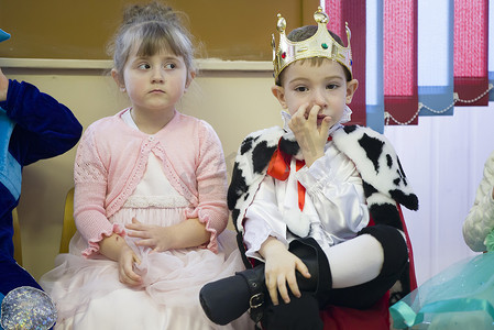 白俄罗斯，Gomil 市，2018 年 12 月 27 日。幼儿园晨会。圣诞假期穿着狂欢节服装的孩子。男孩国王和女孩公主