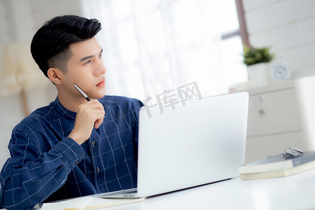 年轻的亚洲商人计划在家里的办公桌上工作和使用笔记本电脑，关于金融、男性学习和学习、商人思维理念、商业和沟通理念的笔记。