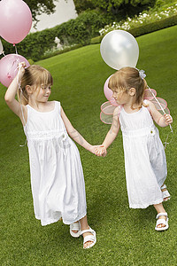 牵着气球摄影照片_在花园里散步时，全长可爱的小伴娘手牵着气球