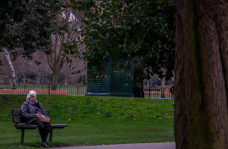 坐在公园长椅上的木椅上的白人老妇。