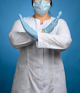 身穿白大衣的女军医，蓝色背景上的面具，双臂交叉