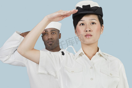 海军敬礼摄影照片_严肃的美国海军女军官和男水手在浅蓝色背景下敬礼的画像