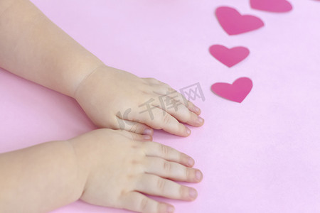 孩子们的手放在带红心的粉红色背景上。