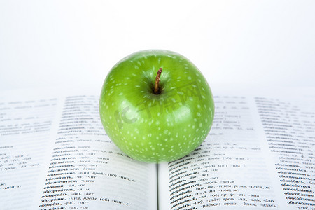 绿色书本摄影照片_书本上的青苹果