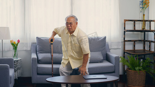 老人爷爷拄着拐杖，靠在地上，从沙发上慢慢站起来