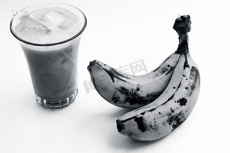 生有机新鲜香蕉及其冰沙或奶昔或香蕉牛奶，放在玻璃杯中，用白色隔开。