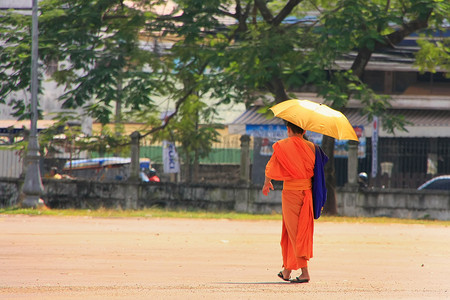 老挝万象街上带雨伞的僧人