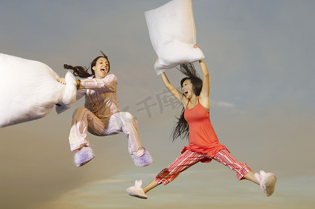古人枕头摄影照片_两名多民族年轻女性在户外半空中进行枕头大战