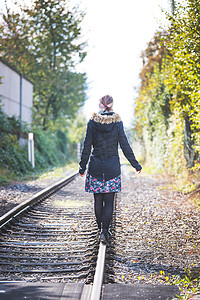 年轻漂亮的女孩在铁路上保持平衡，旅行的概念