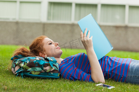 躺在草地上读书笔记的漂亮专心学生