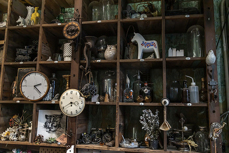 客厅挂钟摄影照片_客厅复古风格的手工木制仿古墙架上的挂钟和收藏品。