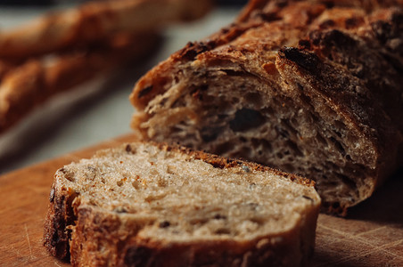 一块切好的无酵母荞麦面包放在一张木桌上的一块木板上，旁边是乡村风格的亚麻桌布上的意大利格里西尼。