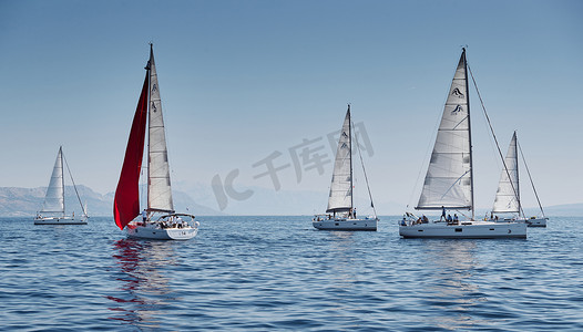 亚得里亚海摄影照片_克罗地亚，亚得里亚海，2019 年 9 月 15 日：背景是帆船比赛、帆船赛、水上帆的倒影、激烈的竞争、鲜艳的色彩、带风车的岛屿