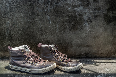 棕色复古高帮帆布运动鞋被放置在旧水泥地板上。
