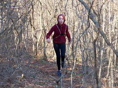 戴耳机的少女背着背包沿着森林小径奔跑