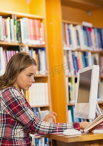 读书成长手册摄影照片_使用计算机的非常集中的学生阅读书