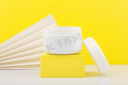 白色打开的罐子在白色桌子上的特写，黄色背景上装饰着白色波浪