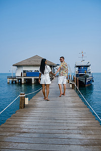春堤摄影照片_泰国芭堤雅 Bangsaray 海滩的木码头，一对夫妇在泰国度假期间在木码头上散步