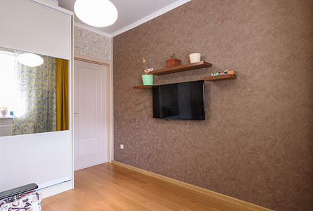 一间小房间的内部、衣柜的景色、一扇入口门和一面带电视和架子的墙