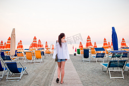 日落时在利古里亚海岸欧洲度假的海滩上的年轻女子
