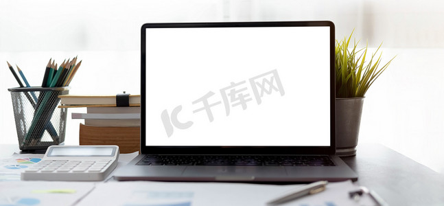 现代办公室中的空白屏幕笔记本电脑和海报工作区背景