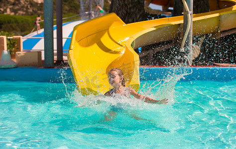 暑假游泳摄影照片_暑假期间在水上乐园滑水的小女孩