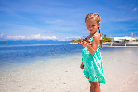 海星可爱摄影照片_热带海滩上手里拿着海星的可爱小女孩