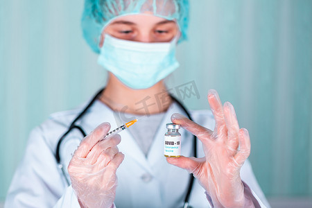 大药瓶摄影照片_身穿制服和戴面罩的手套的医生或护士在实验室拿着带有 COVID-19 冠状病毒疫苗标签的药瓶疫苗瓶