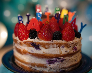 带蜡烛蛋糕摄影照片_带蜡烛和蓝色气球的生日蛋糕