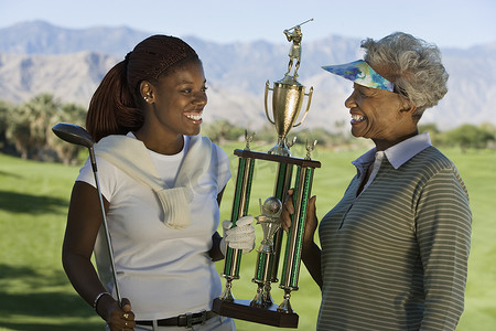 高尔夫球奖杯摄影照片_拿着高尔夫球奖杯的祖母和孙女