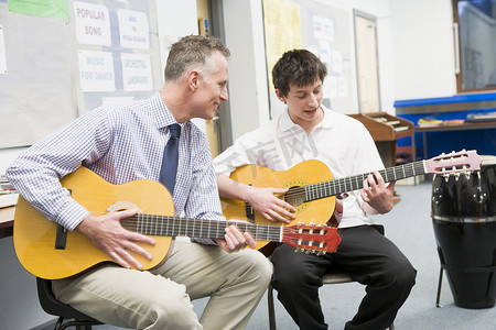 男学生在课堂上接受老师的吉他课