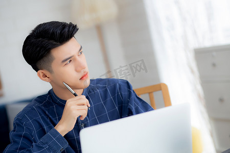 年轻的亚洲商人计划在家里的办公桌上工作和使用笔记本电脑，关于金融、男性学习和学习、商人思维理念、商业和沟通理念的笔记。