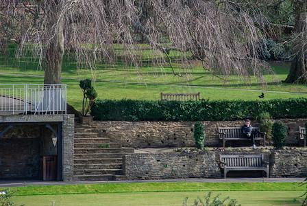 一名男子坐在吉尔福德城堡和庭院的木凳上放松。