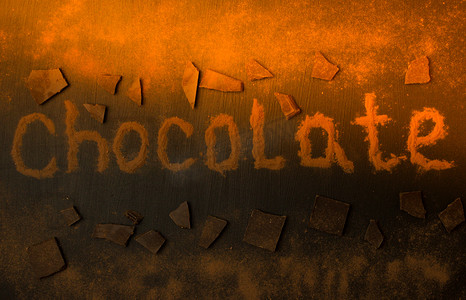 用可可粉制成的题词巧克力，在黑色石墨背景上添加巧克力和巧克力粉，带有阳光