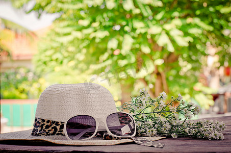 木地板和自然背景上的帽子眼镜和花