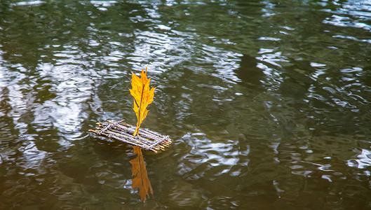 玩具帆船摄影照片_带帆的玩具筏漂浮在湖面上